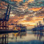 Containerkräne im Hafen bei Sonnenuntergang – angetrieben durch esco-Frequenzumrichter mit Kranfunktion, sicherer Lastregelung und Drehmomentüberwachung.